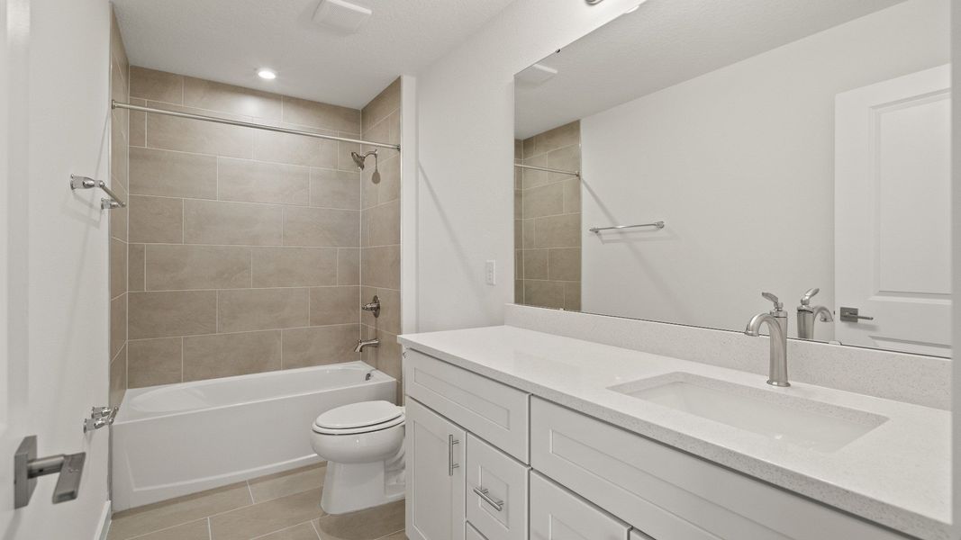 Stylish second bathroom features dual sinks, plenty of counter space, and a tub-shower combo with sleek tile surround