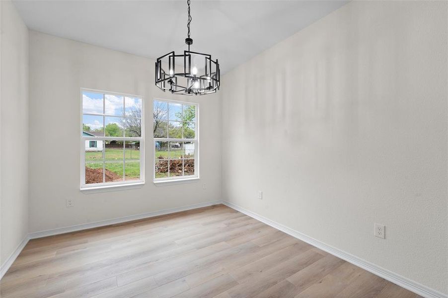 Unfurnished dining area featuring light wood-type flooring and a chandelier
