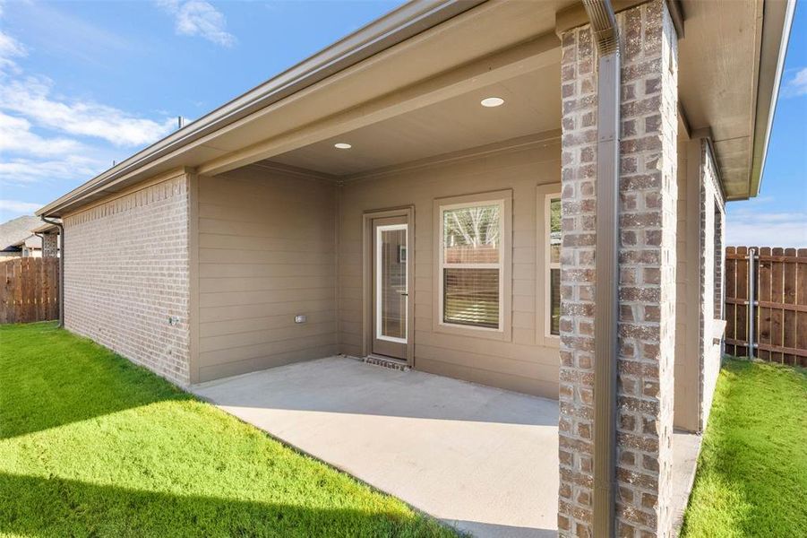 View of exterior entry featuring a patio area and brick siding