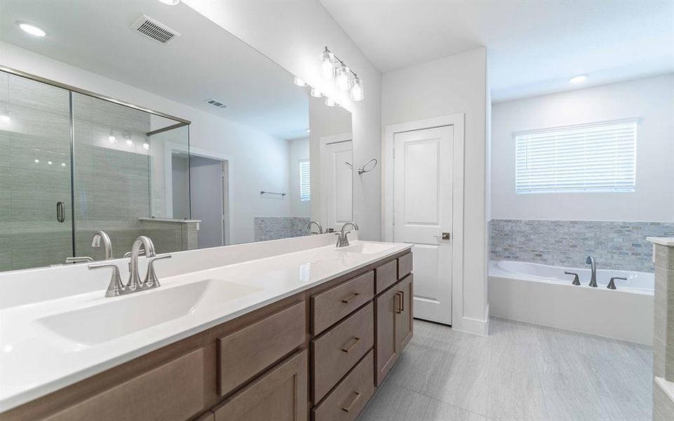 Dual vanity with white countertops and brushed nickel fixtures, complemented by a large mirror and overhead lighting