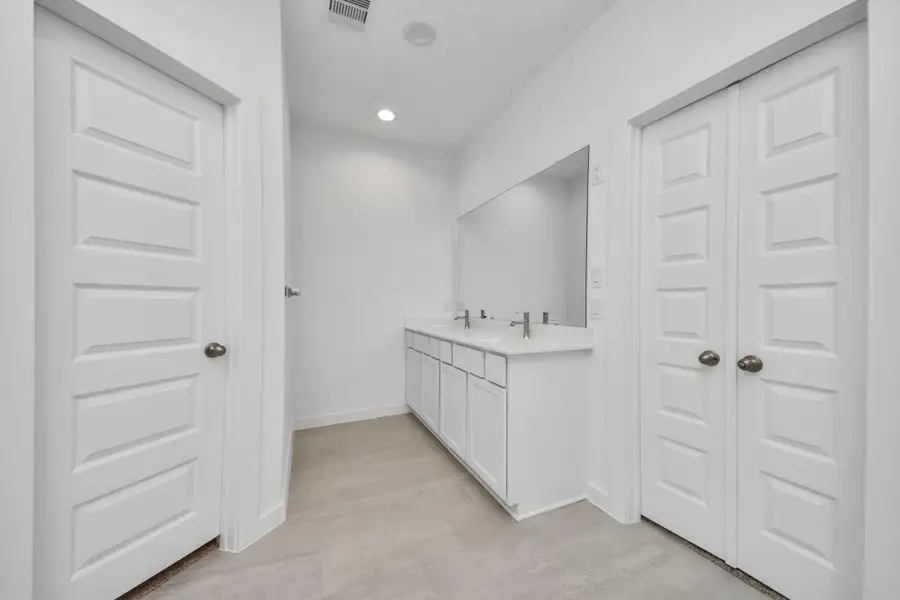 Elevate your daily routine at the elegant vanity, now equipped with double sinks, light countertops, modern hardware, and beautiful recessed lights. Sample photo of completed home with similar floor plan. Actual colors and selections may vary.