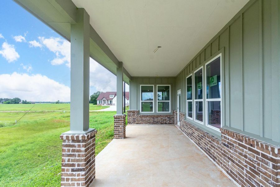 Spacious covered porch with charming brick accents offers serene views of lush green fields, perfect for relaxing outdoors. Spacious covered porch with charming brick accents offers serene views of lush green fields, perfect for relaxing outdoors.