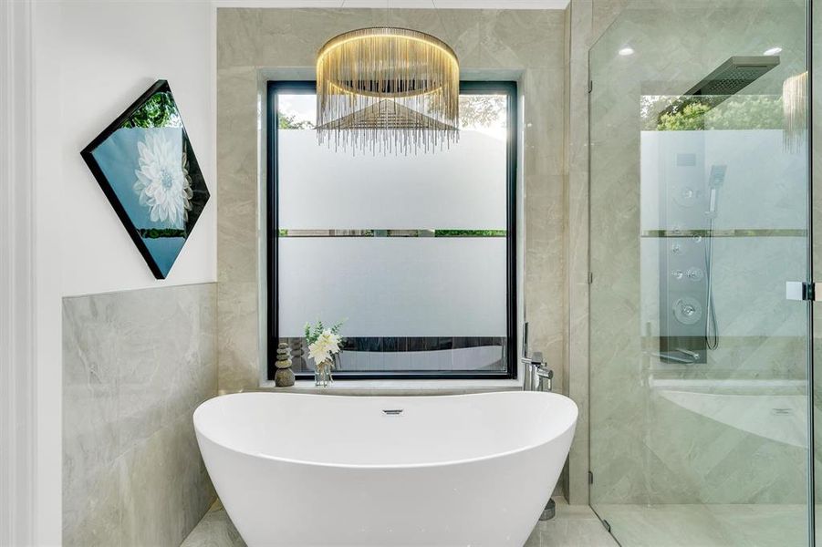 Bathroom with a freestanding tub, a shower stall, and tile walls