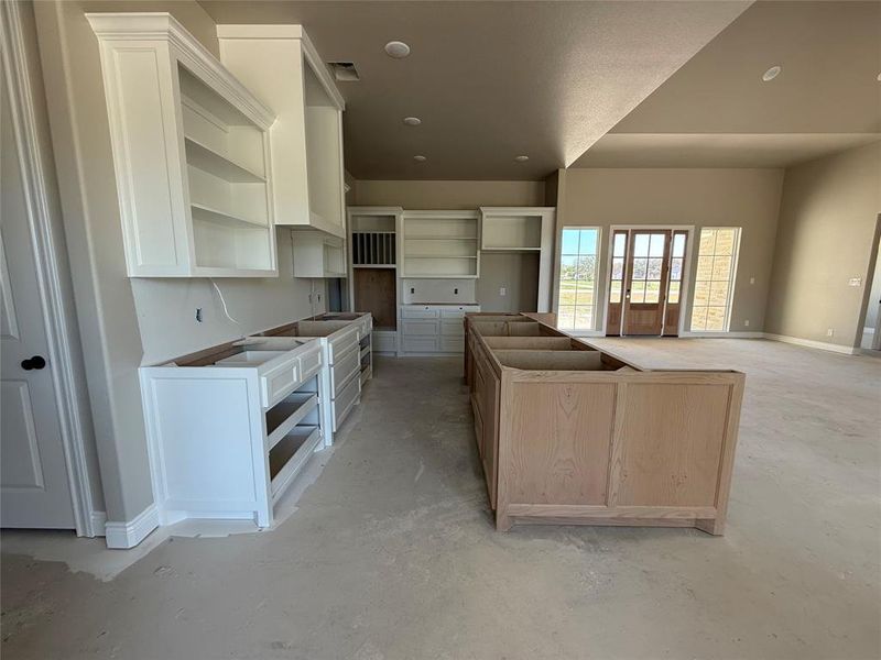 Kitchen featuring a kitchen island, concrete floors, two tone cabinets, and open floor plan