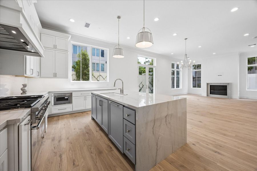 Oversized island with waterfall countertops overlook the bright and spacious living room.