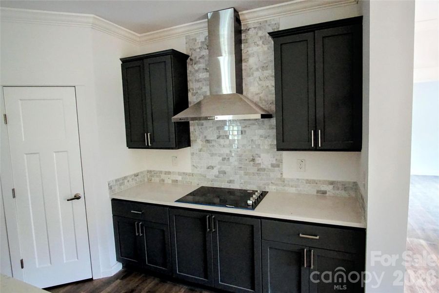 Cooktop with exhaust hood and tiled backsplash