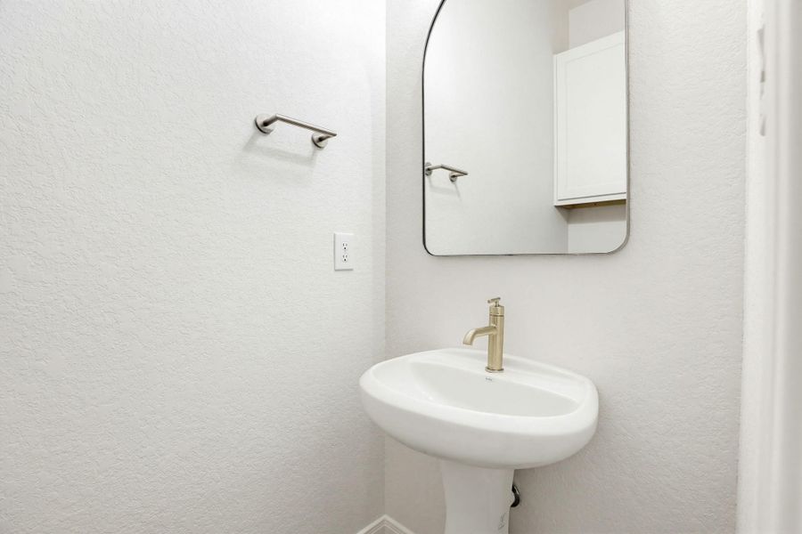 A sleek pedestal sink and contemporary mirror elevate this well-appointed powder room.