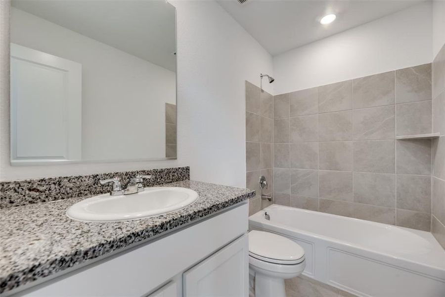 Full bathroom with tiled shower / bath, vanity, and toilet