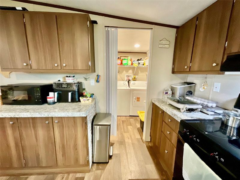 Kitchen featuring wood-finish cabinetry, light-toned countertops, and wood-finish flooring