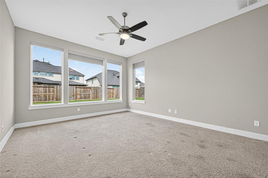 Primary bedroom with ceiling fan and pull down shades.