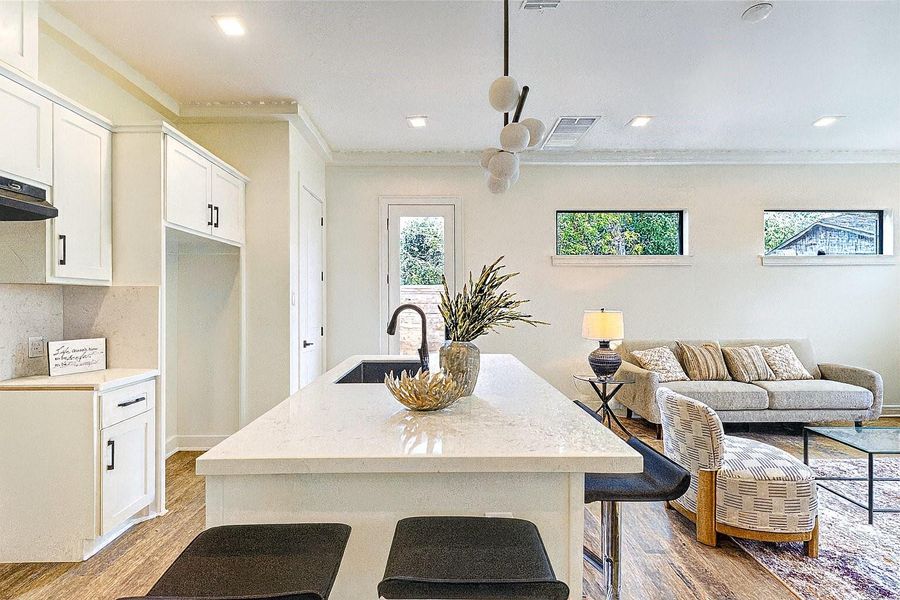Bright and modern kitchen with a large island and seating, white cabinetry, stainless steel appliances, and direct access to the backyard for easy indoor-outdoor living.
