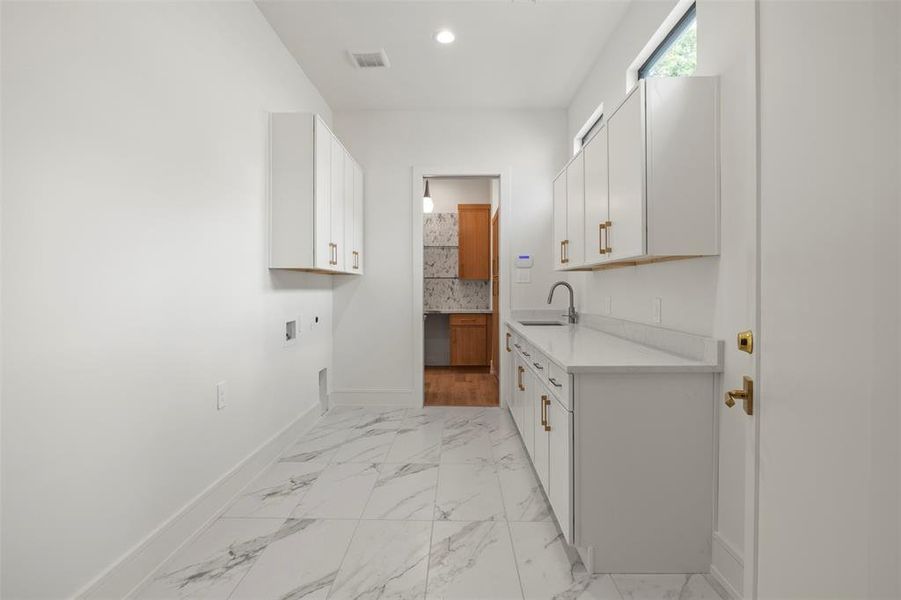 Laundry room with cabinet space, hookup for an electric dryer, light marble finish floors, and washer hookup Laundry room with cabinet space, hookup for an electric dryer, light marble finish floors, and washer hookup