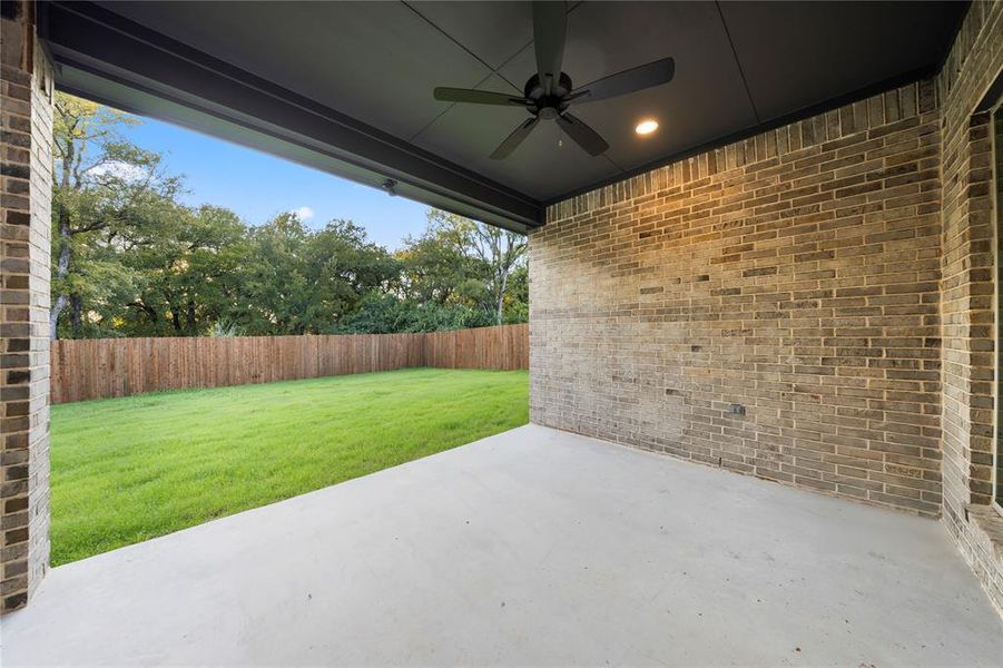 Fenced backyard with a patio area and ceiling fan
