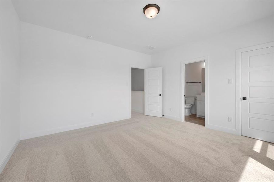 Unfurnished bedroom with light colored carpet and ensuite bathroom