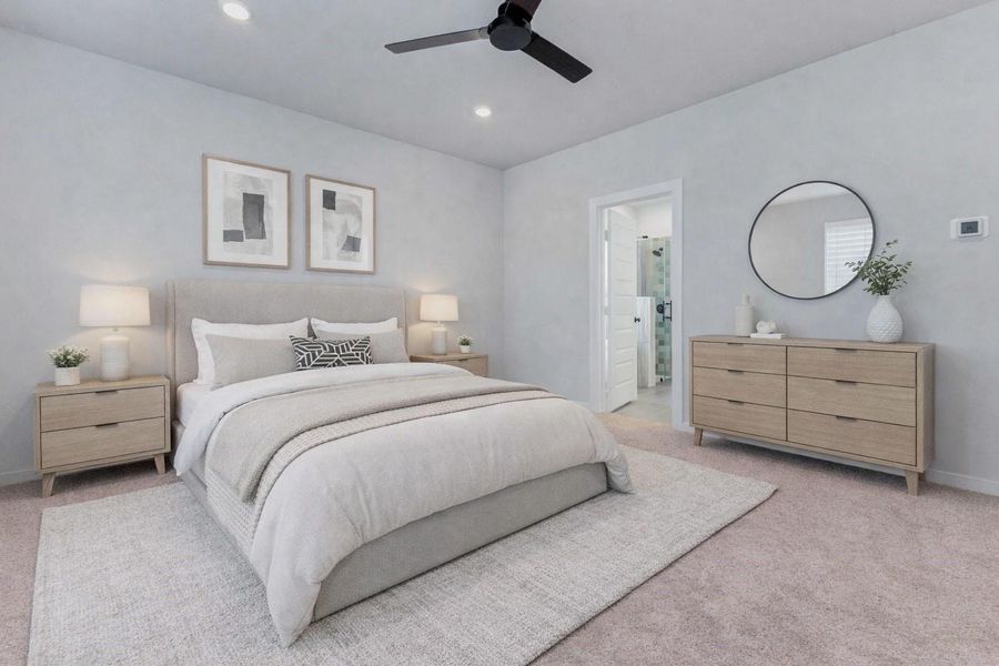 Retreat to the peaceful first-floor primary bedroom, where plush carpeting, recessed lighting, and a modern ceiling fan set the tone for rest and relaxation. Direct access to the ensuite bath makes this space the ultimate private getaway within your home. This photo has been virtually staged for visual reference.