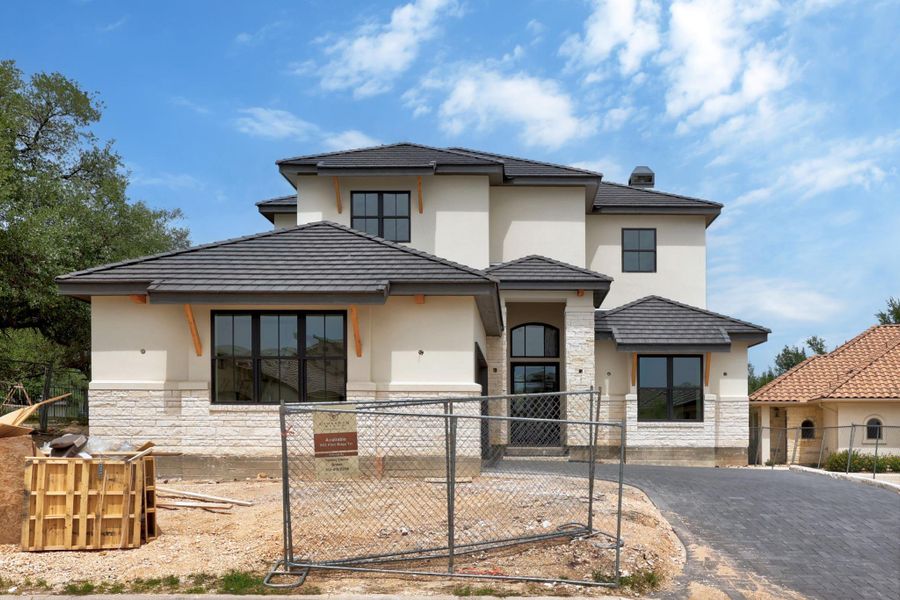Contemporary stucco and stone exterior featuring multiple gables and a dark tile roof