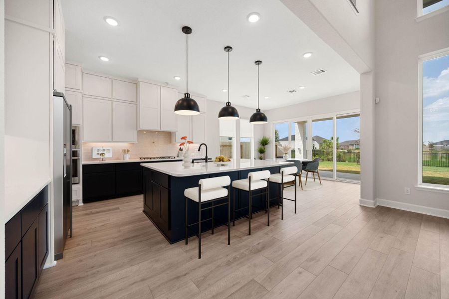 Chef's dream gourmet kitchen showcasing a massive central prep island with high-end quartz countertops, a modern undermount sink, and comfortable breakfast bar seating. This stunning culinary space features an upscale two-tone cabinetry design with crisp white upper cabinets extending to the ceiling and sleek dark lower cabinetry. Equipped with premium stainless steel appliances, a modern tile backsplash, and designer matte black pendant lighting. *Virtually Staged Chef's dream gourmet kitchen showcasing a massive central prep island with high-end quartz countertops, a modern undermount sink, and comfortable breakfast bar seating. This stunning culinary space features an upscale two-tone cabinetry design with crisp white upper cabinets extending to the ceiling and sleek dark lower cabinetry. Equipped with premium stainless steel appliances, a modern tile backsplash, and designer matte black pendant lighting. *Virtually Staged