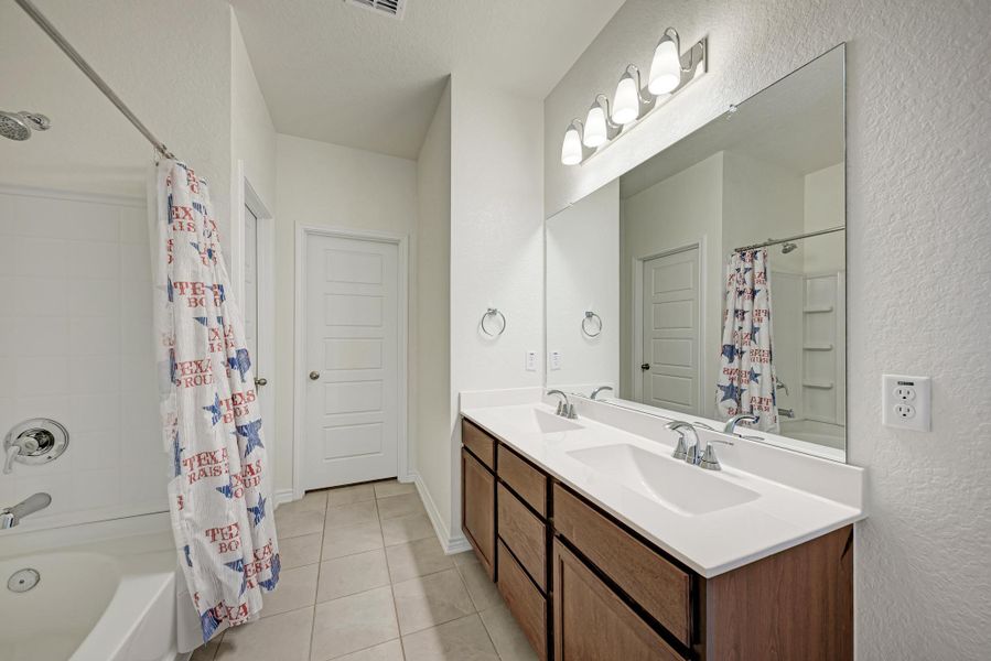 A well-lit bathroom features a large vanity with dual sinks and a spacious shower-tub combination.