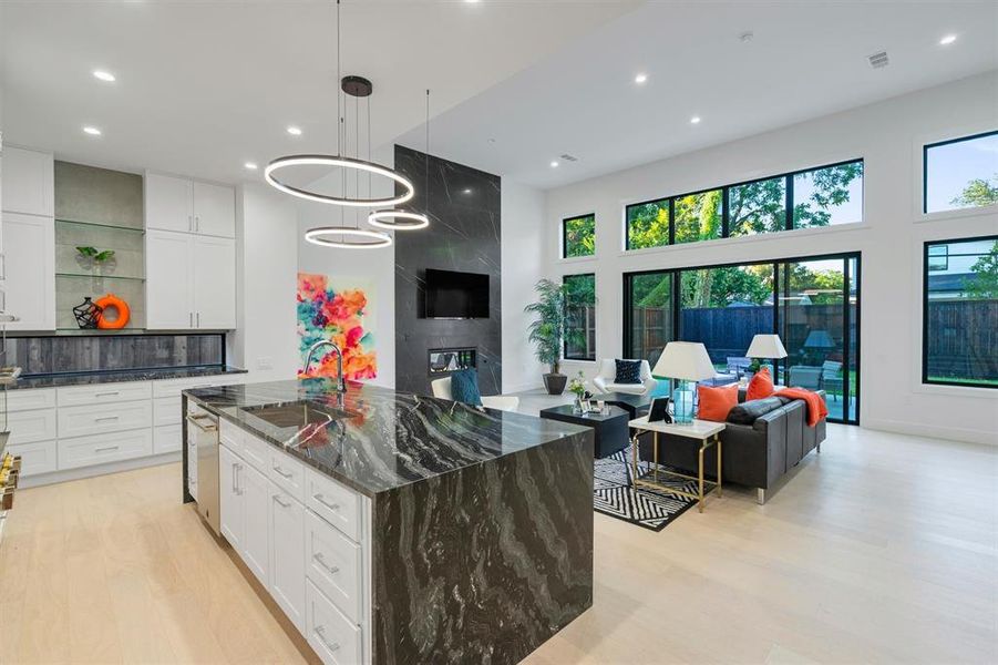Kitchen featuring dark stone counters, open floor plan, a kitchen island, white cabinets, and a high ceiling Kitchen featuring dark stone counters, open floor plan, a kitchen island, white cabinets, and a high ceiling