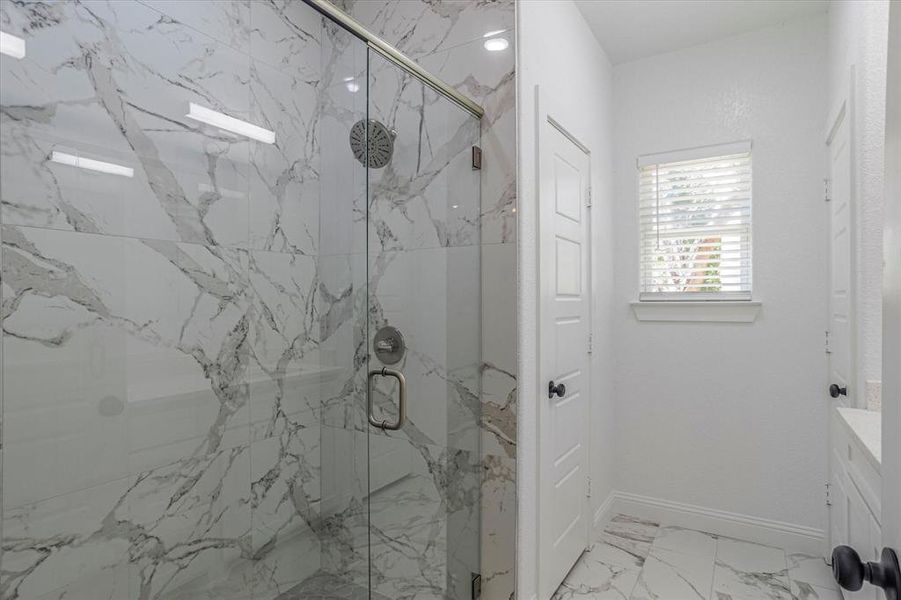 Bathroom with tile floors, a shower with door, and vanity