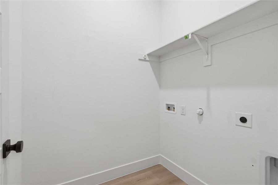 Laundry room with light wood-style floors, hookup for a washing machine, hookup for an electric dryer, and hookup for a gas dryer Laundry room with light wood-style floors, hookup for a washing machine, hookup for an electric dryer, and hookup for a gas dryer