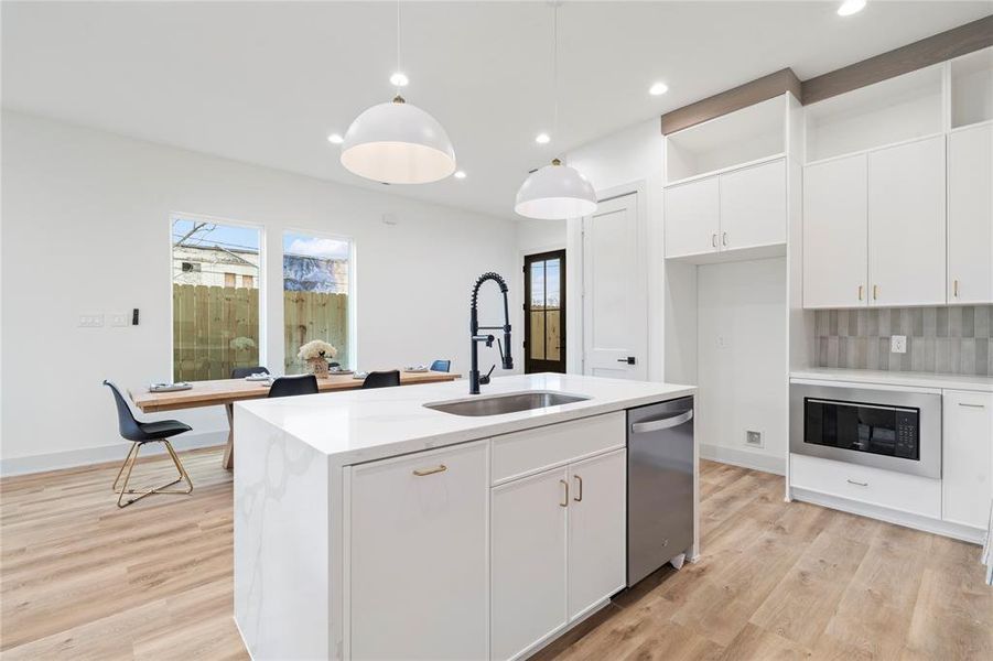 A gourmet chef’s kitchen featuring a sleek, modern design with quartz waterfall countertops on a spacious island, providing both workspace and casual seating.