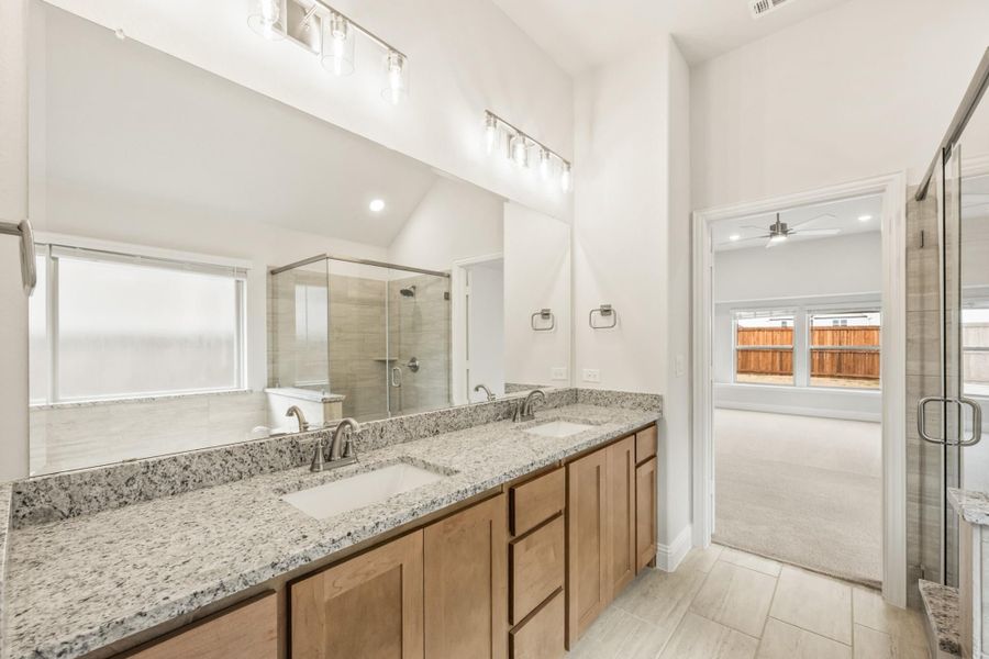 Ensuite bathroom with double granite vanity, wood cabinets, and glass walk-in shower Ensuite bathroom with double granite vanity, wood cabinets, and glass walk-in shower