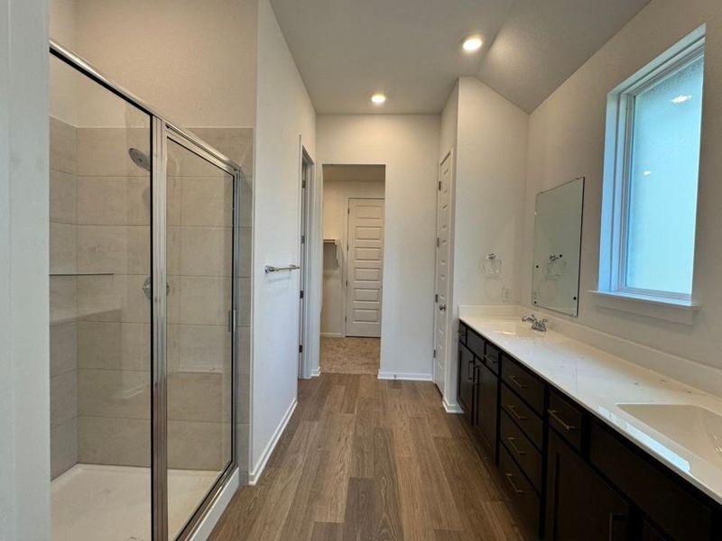 Bathroom featuring a shower stall, dark wood finished floors, double vanity, and recessed lighting