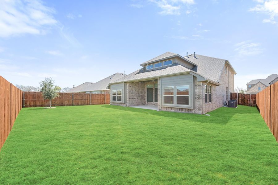Brick home rear exterior with large fenced backyard, covered patio, and green lawn Brick home rear exterior with large fenced backyard, covered patio, and green lawn
