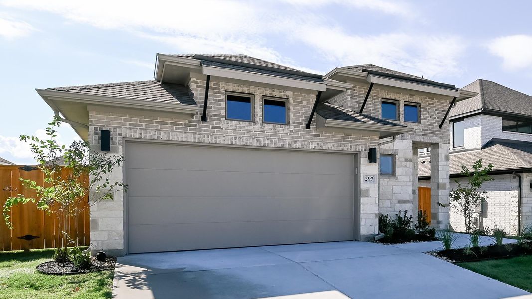 View of front of property with driveway, brick siding, a garage, and stone siding