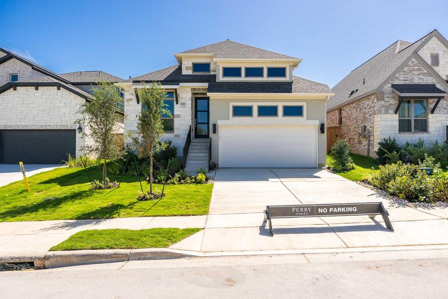 View of front of home with concrete driveway, a front lawn, a shingled roof, stone siding, and an attached garage View of front of home with concrete driveway, a front lawn, a shingled roof, stone siding, and an attached garage