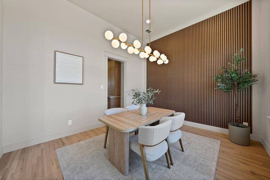 Dining space featuring an accent wall, light wood-style floors, a chandelier, and wooden walls