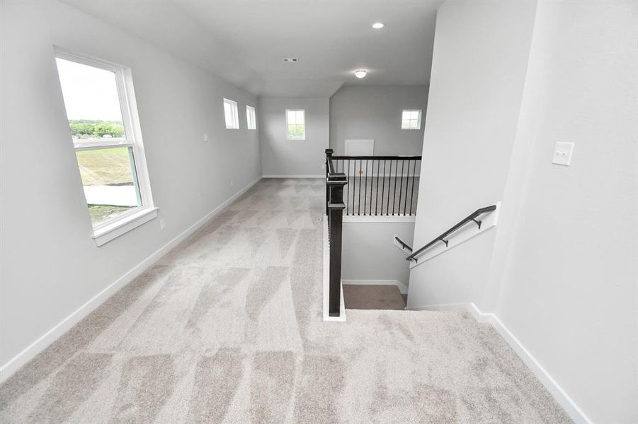 Ascend to relaxation in this fantastic game room! Ideal for both casual gatherings and adult gaming, it boasts plush carpet, lofty ceilings, custom paint, and ample windows for abundant natural light.  Sample photo of completed home with similar plan. As built color and selections may vary.