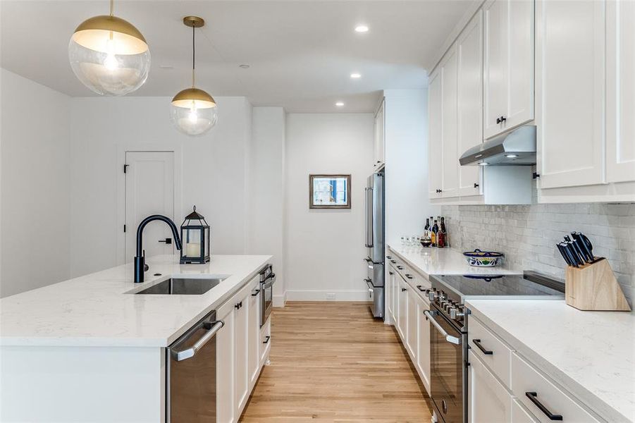 Kitchen featuring appliances with stainless steel finishes, light stone counters, white cabinets, recessed lighting, and pendant lighting Kitchen featuring appliances with stainless steel finishes, light stone counters, white cabinets, recessed lighting, and pendant lighting