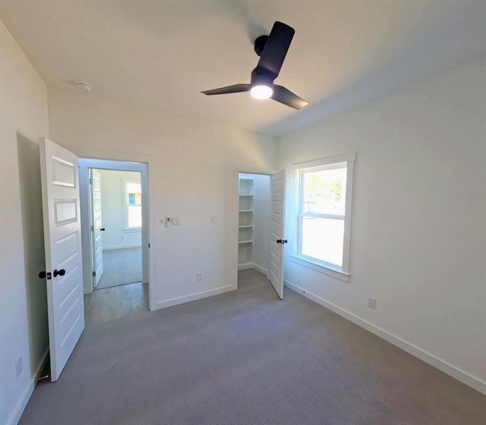 Unfurnished bedroom featuring dark colored carpet, a spacious closet, and ceiling fan Unfurnished bedroom featuring dark colored carpet, a spacious closet, and ceiling fan