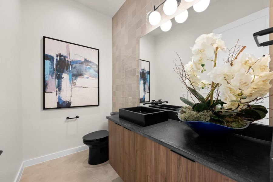 A well-appointed powder room features sleek black fixtures and a floating vanity. A well-appointed powder room features sleek black fixtures and a floating vanity.