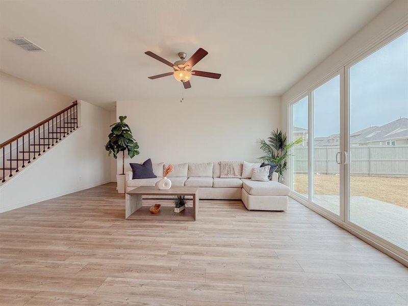 Living area featuring ceiling fan, stairway, visible vents, and light wood-style floors