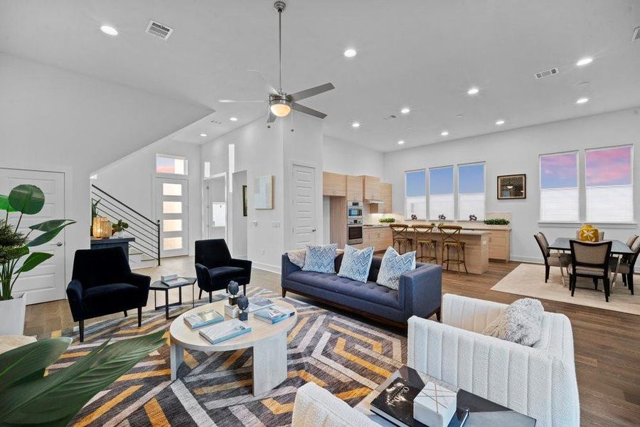Living room featuring wood finished floors, a ceiling fan, stairs, recessed lighting, and a high ceiling