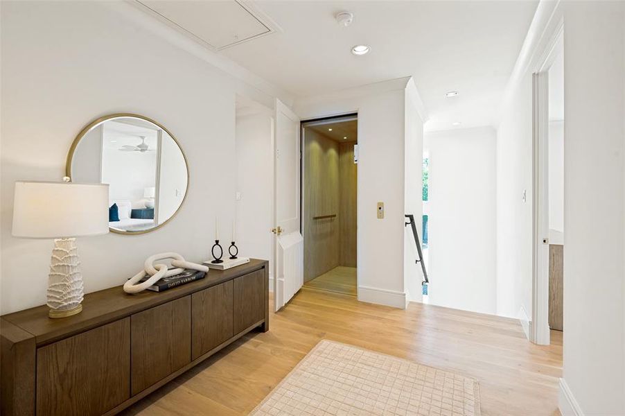 Hallway featuring wood-finish flooring, recessed lighting, crown molding, and a built-in elevator with wood paneling