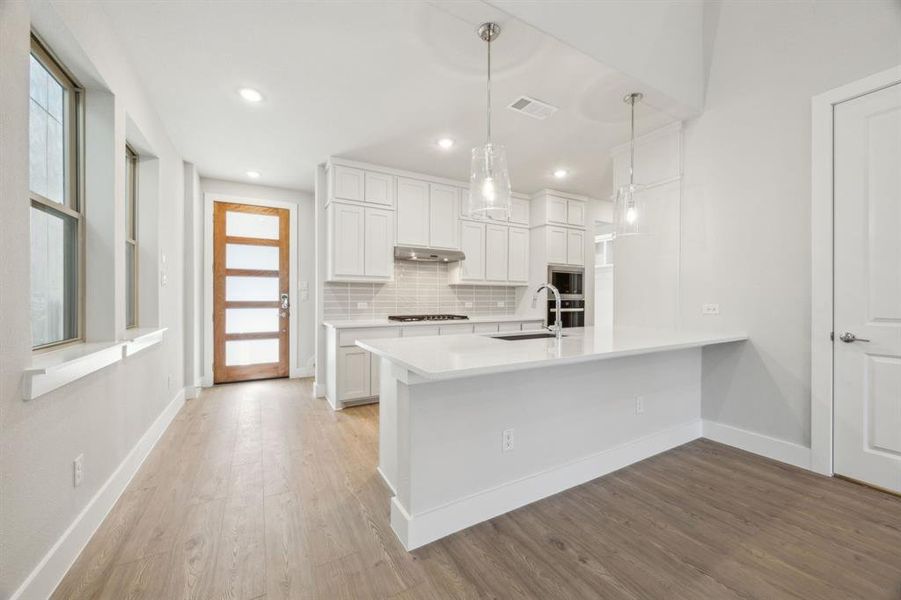 Kitchen featuring pendant lighting, sink, appliances with stainless steel finishes, backsplash, and white cabinets