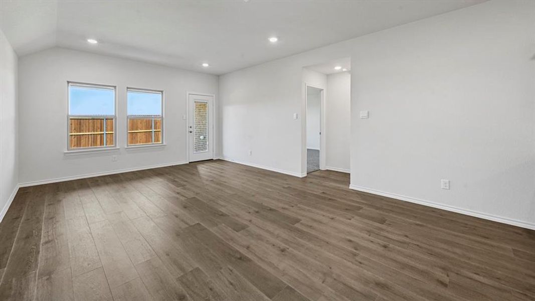 Spacious living area featuring wood-finish flooring, recessed lighting, and a vaulted ceiling