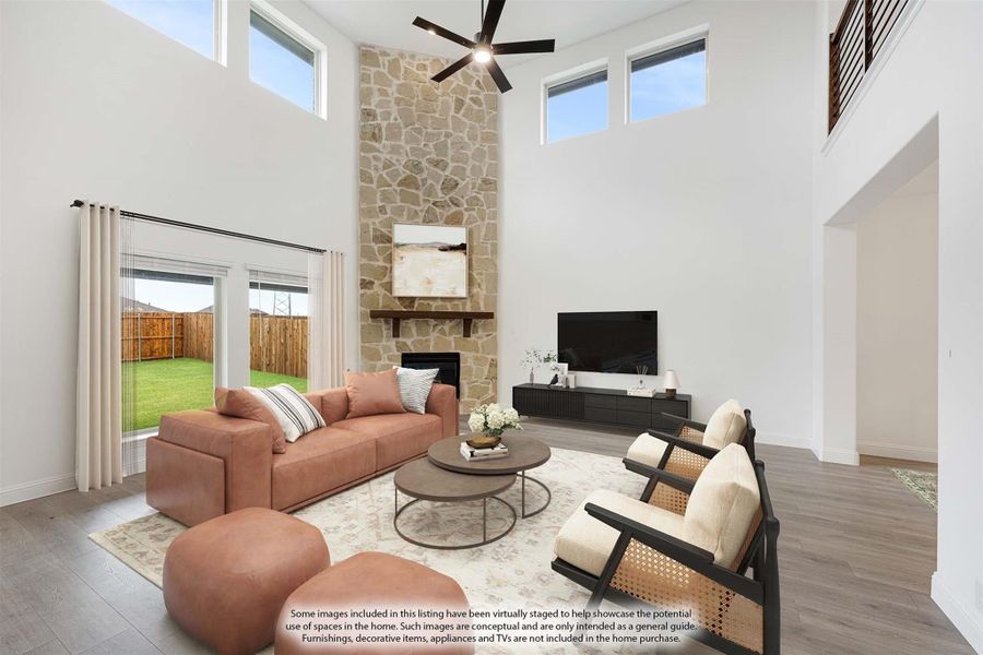 Living room with two-story ceiling, floor-to-ceiling stone fireplace, ceiling fan, and hardwood floors Living room with two-story ceiling, floor-to-ceiling stone fireplace, ceiling fan, and hardwood floors