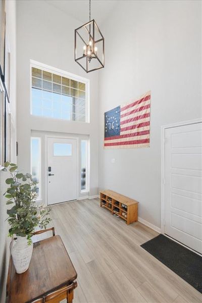 Foyer entrance with a high ceiling, a chandelier, and light wood finished floors Foyer entrance with a high ceiling, a chandelier, and light wood finished floors
