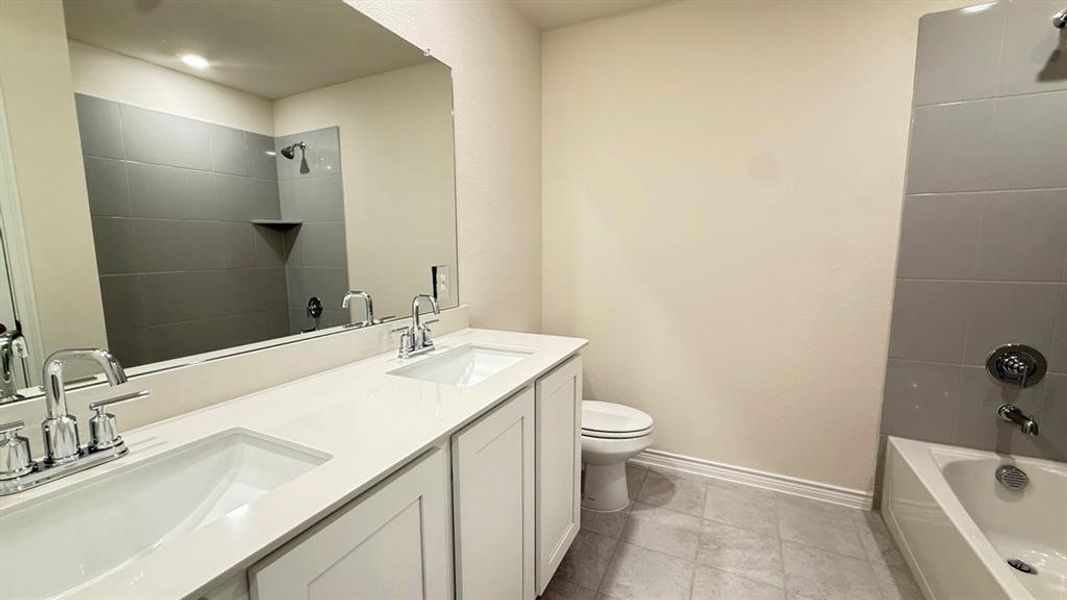 Bathroom featuring  shower combination, double vanity, and light tile patterned flooring