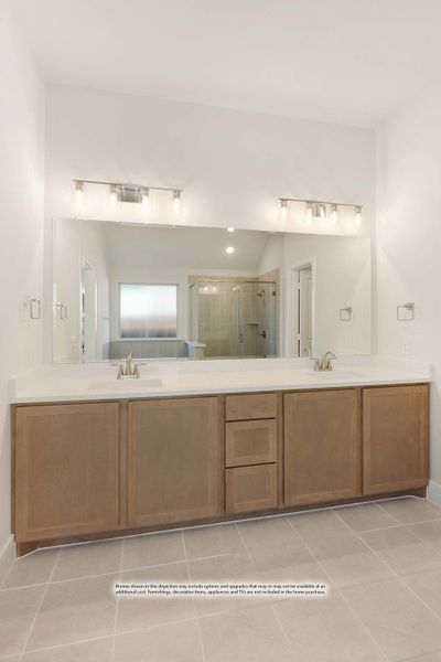 Bathroom double vanity with wood cabinets, white countertop, two sinks, and large mirror with overhead lighting Bathroom double vanity with wood cabinets, white countertop, two sinks, and large mirror with overhead lighting
