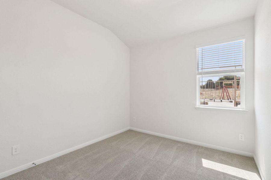 Carpeted spare room featuring baseboards and vaulted ceiling Carpeted spare room featuring baseboards and vaulted ceiling