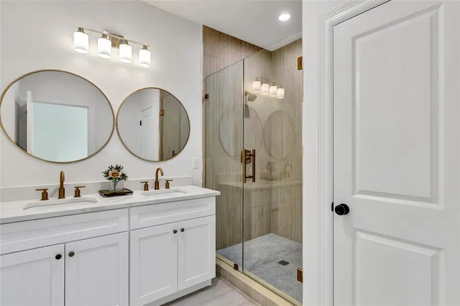 Elegant master bath with a double-sink vanity, private toilet, and a sleek frameless glass walk-in shower.