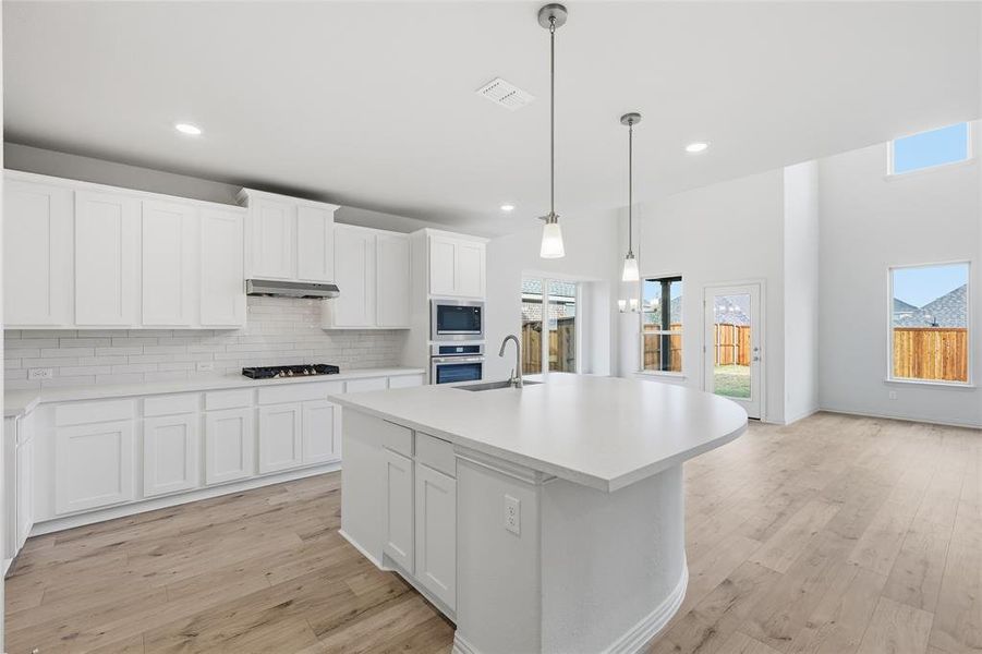 Kitchen featuring white cabinetry, hanging light fixtures, light wood-style floors, recessed lighting, and a high ceiling Kitchen featuring white cabinetry, hanging light fixtures, light wood-style floors, recessed lighting, and a high ceiling