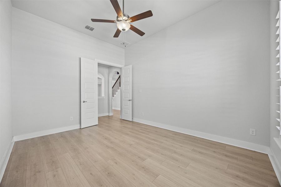 A versatile space features light-toned wood flooring and a modern ceiling fan, offering adaptable living possibilities.