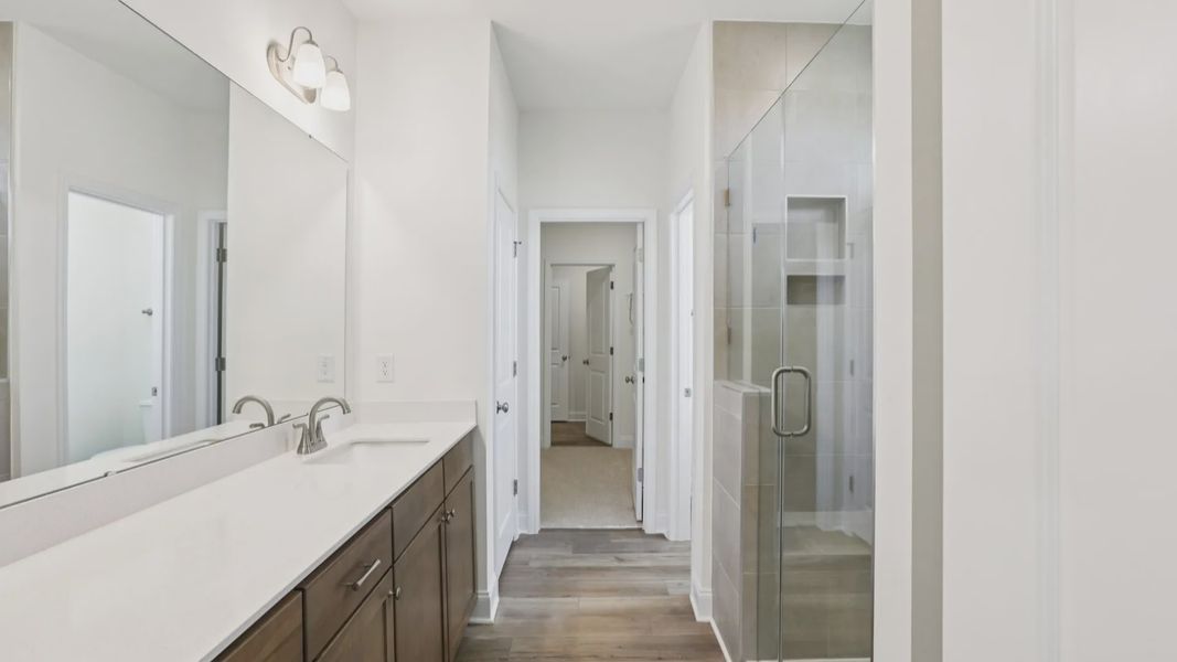 Pendleton home plan primary bathroom with tile shower, dual vanities and linen closet
